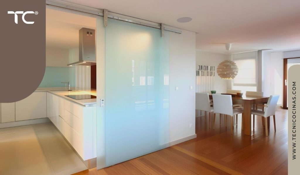 Cerramiento corredizo de vidrio satinado entre cocina en L y comedor en apartamento residencial