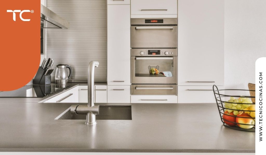 Campana extractora y grifería en acero en una cocina con acabados blancos