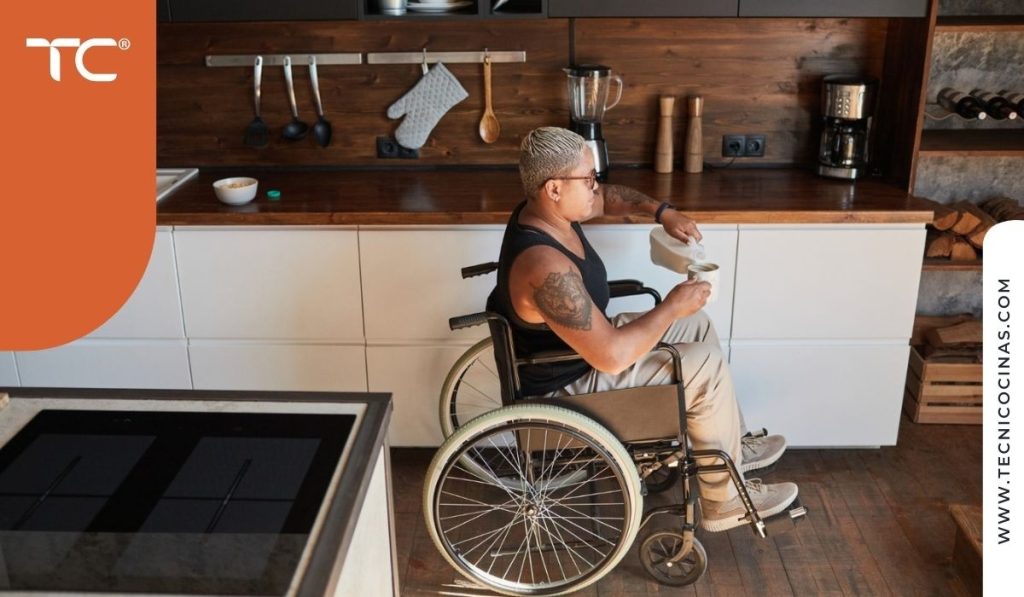 Persona en silla de ruedas trabajando en la encimera de una cocina residencial adaptada a su altura