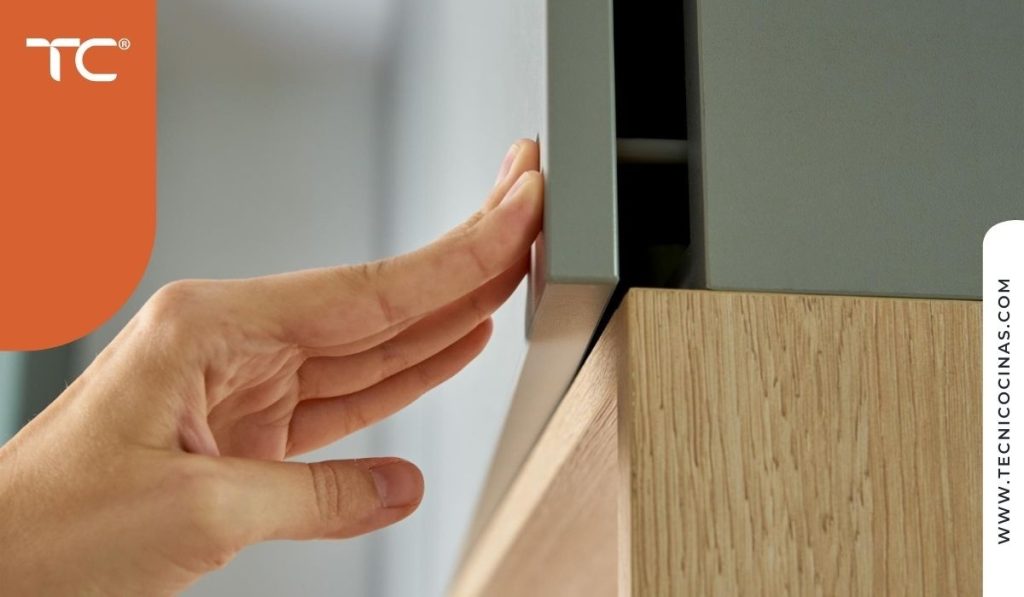 Detalle de mano abriendo un cajón de cocina con sistema push-to-open sin necesidad de agarre