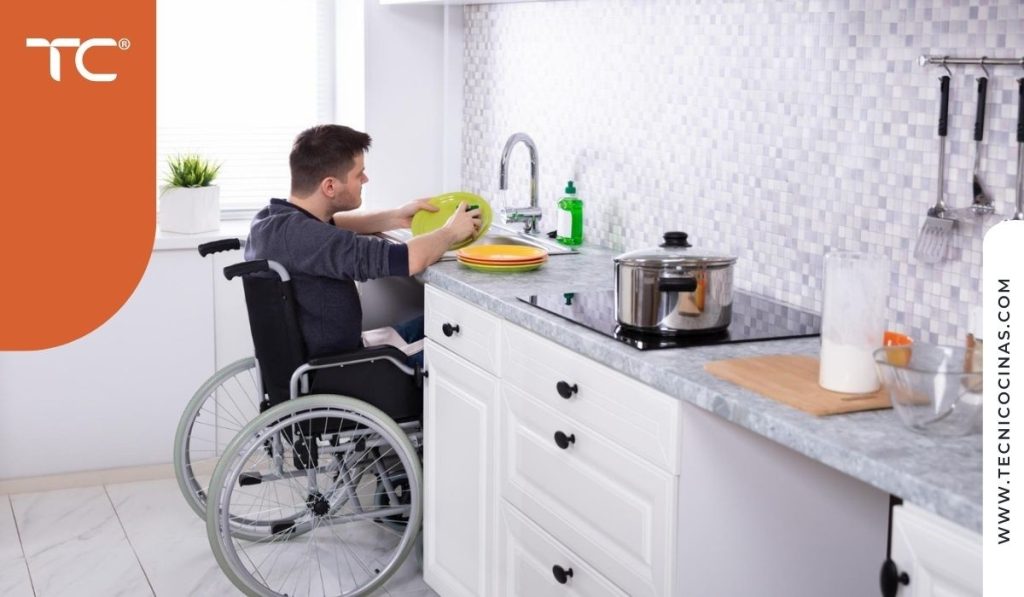 Hombre en silla de ruedas trabajando cómodamente en una encimera a altura adaptada en cocina luminosa