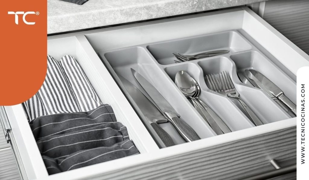 Cajón de cocina completamente extraído mostrando cubiertos y utensilios accesibles desde la posición sentada