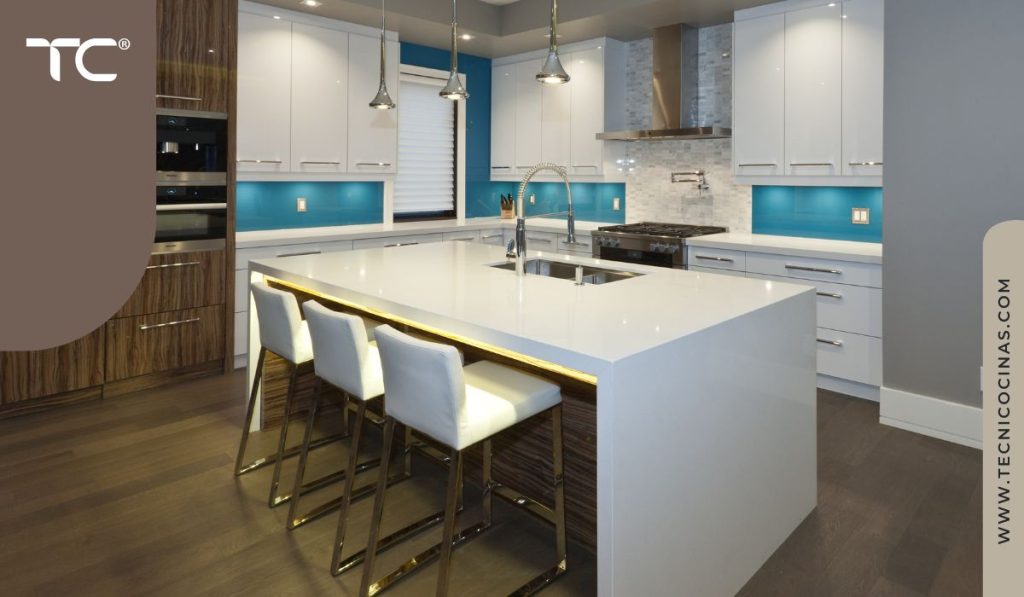 Cocina con isla con fondo celeste turquesa y conexión visual con zona social abierta.