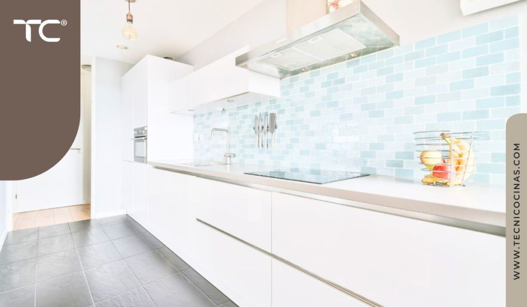 Cocina blanca con salpicadero en mosaico celeste claro, ideal para espacios con poca luz.