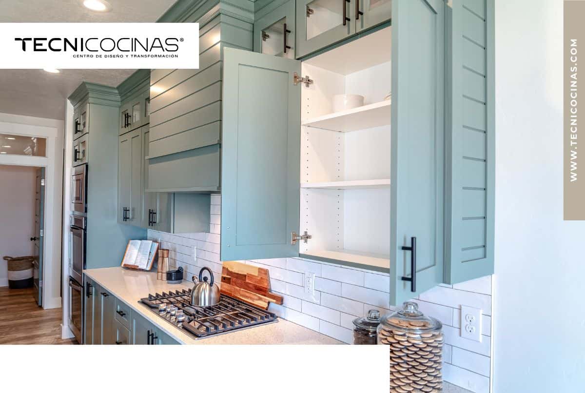Cocina moderna con gabinetes celestes y acabado brillante, iluminación natural y diseño continuo.