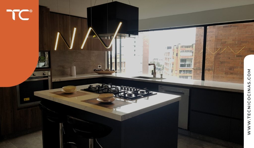 Cocina integral moderna con isla, cocción empotrada y grifo sobre mesón junto a la ventana.