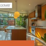 Cocina integral moderna con isla central, iluminación natural abundante y vegetación interior.