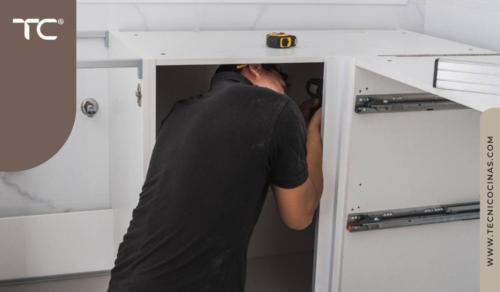 Instalador ajustando el herraje dentro de un gabinete inferior de cocina