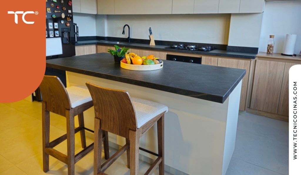 Cocina integral con isla, mesón en piedra negra y gabinetes en tono madera