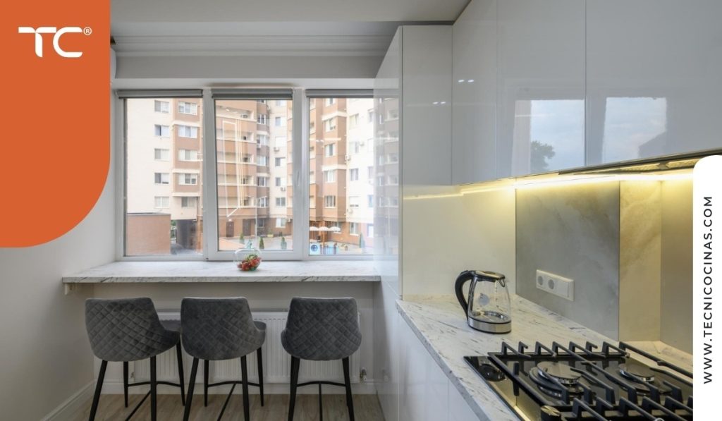 Cocina de apartamento urbano con ventana hacia edificios.