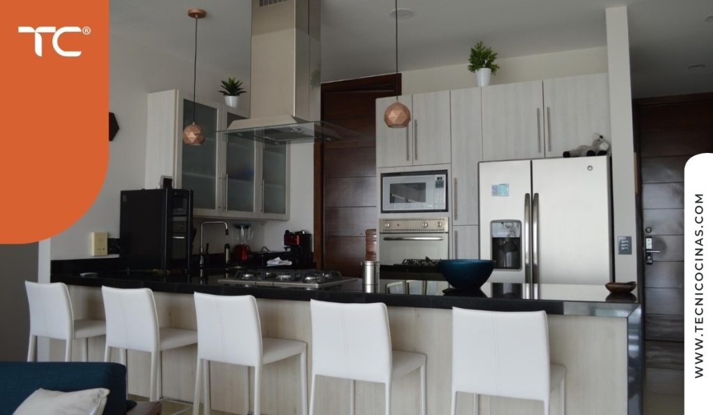 Cocina integral habitada con campana de isla y espacio abierto hacia sala.
