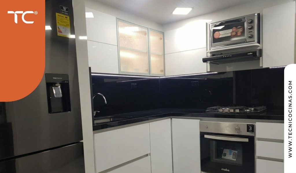 Cocina en L sin ventana con vitrinas superiores de vidrio acanalado iluminadas